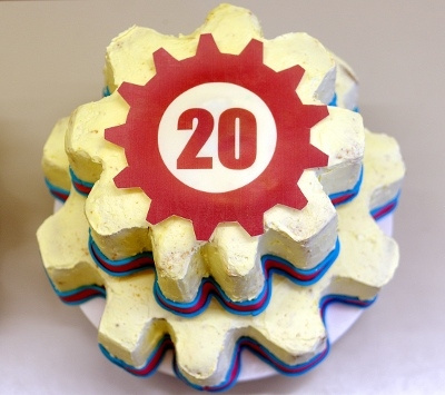 A cake shaped like stacked gears (the fosdem logo is a gear with two dots inside), on top a gear-shaped plaquette with the number 20