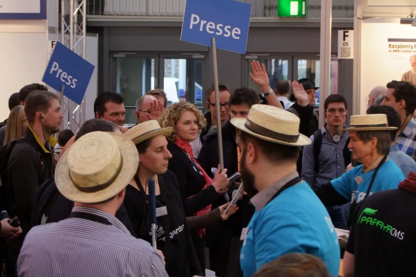 Several people with straw hats turned to a group holding press signs