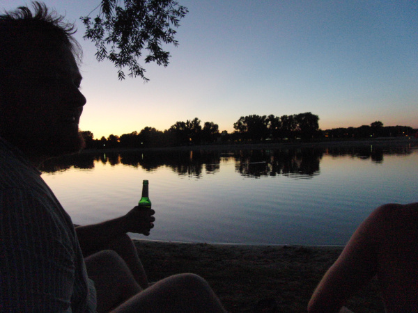 Silhouetten von zwei Personen, die im Sonnenuntergangs-Dämmerlicht auf einen See blicken