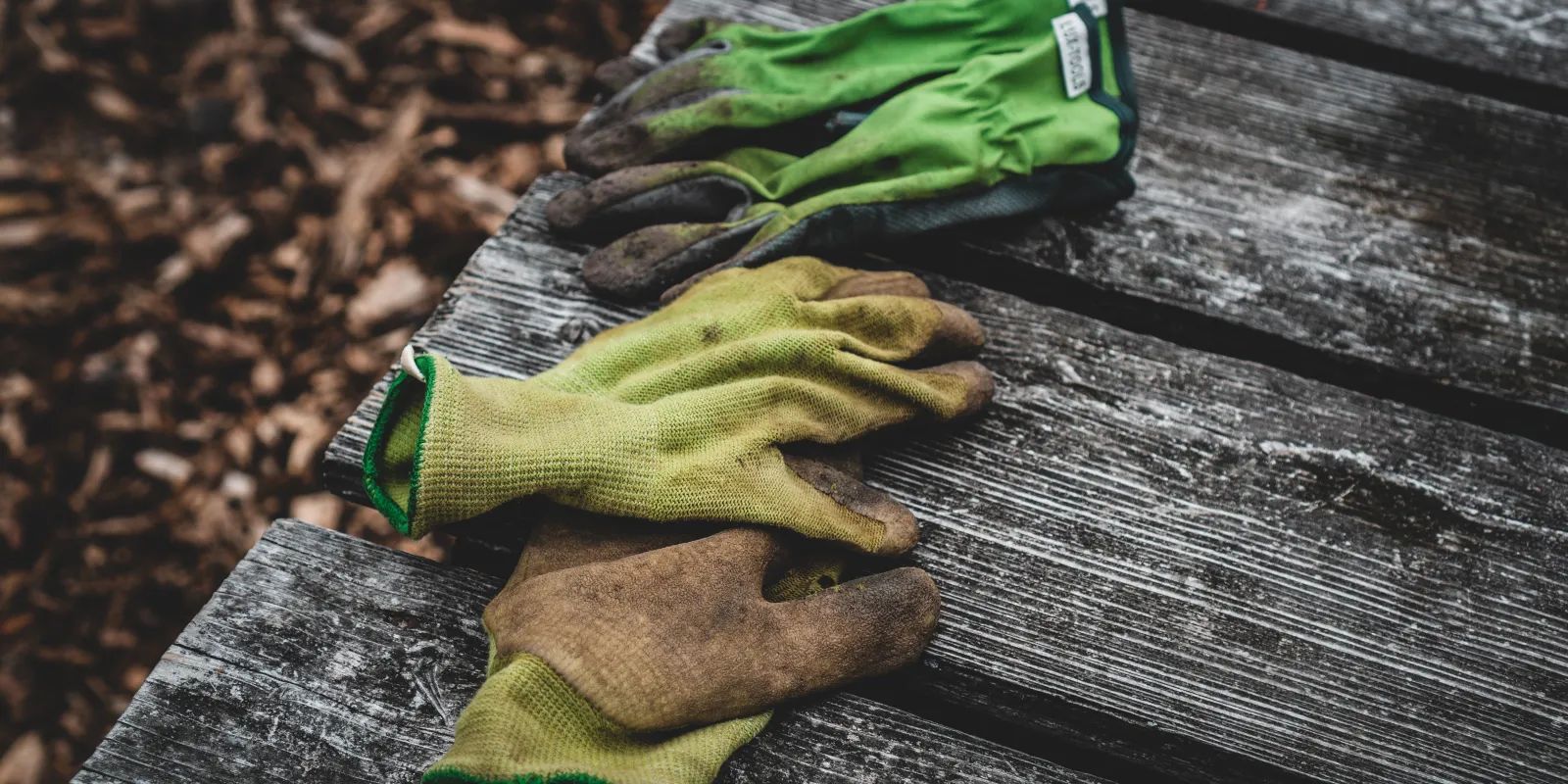 Four dirty working gloves on a weather-beaten wooden table