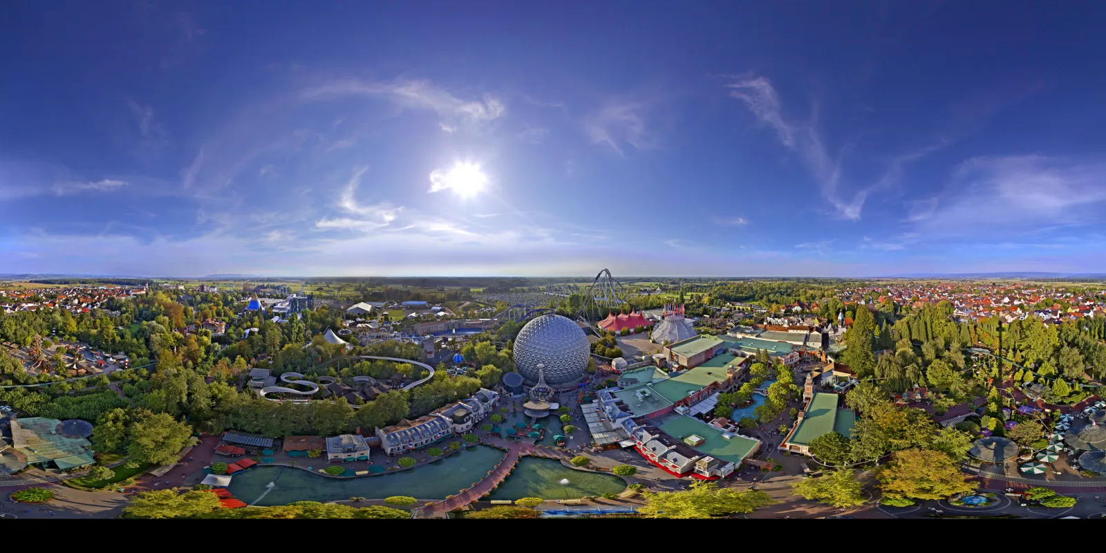 Bird's eye panorama over the amusement park in morning sunshine