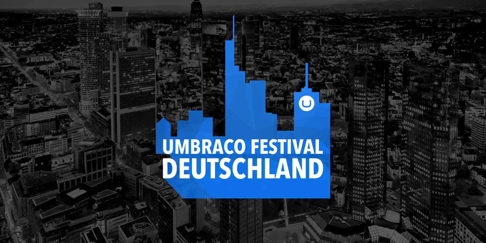 Vor einem abgedunkelten Schwarzweißfoto einer Großstadt eine blaue Silhouette von Hochhäusern, darin Text: Umbraco Festival Deutschland