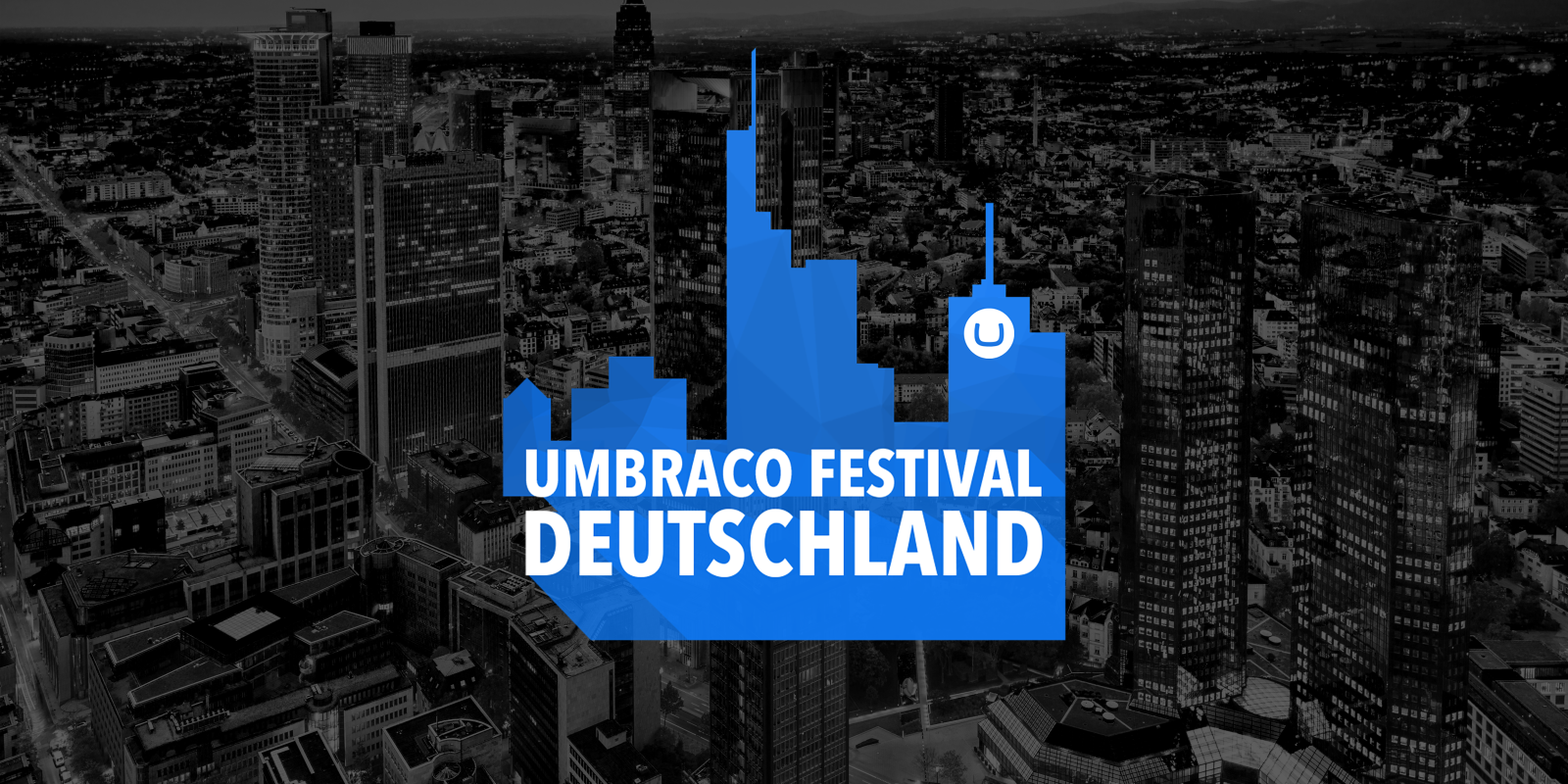 Vor einem abgedunkelten Schwarzweißfoto einer Großstadt eine blaue Silhouette von Hochhäusern, darin Text: Umbraco Festival Deutschland