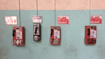 Four different phone boxes are mounted in slightly different heights on shabby turquoise wall